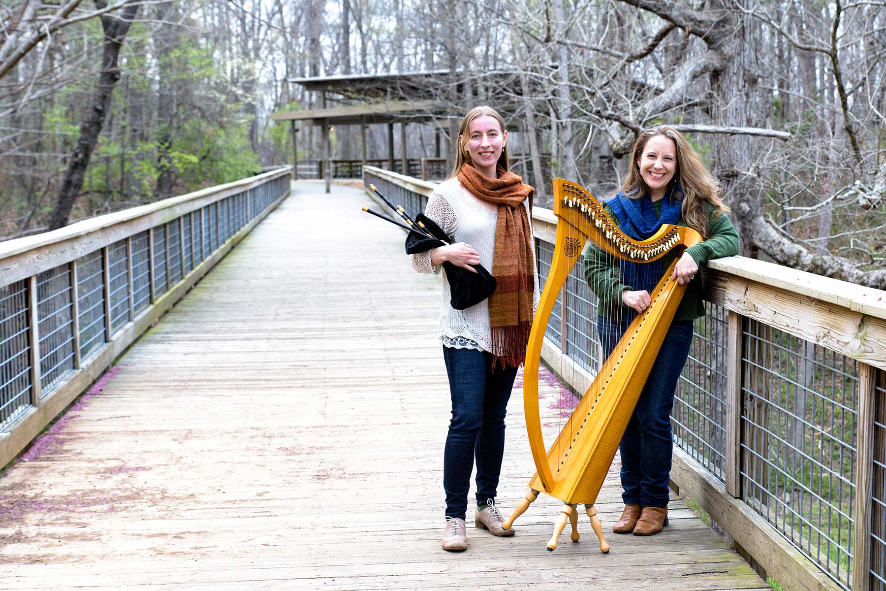 Rosalind holding the Scottish smallpipes and Kelly with her harp on a bridge.